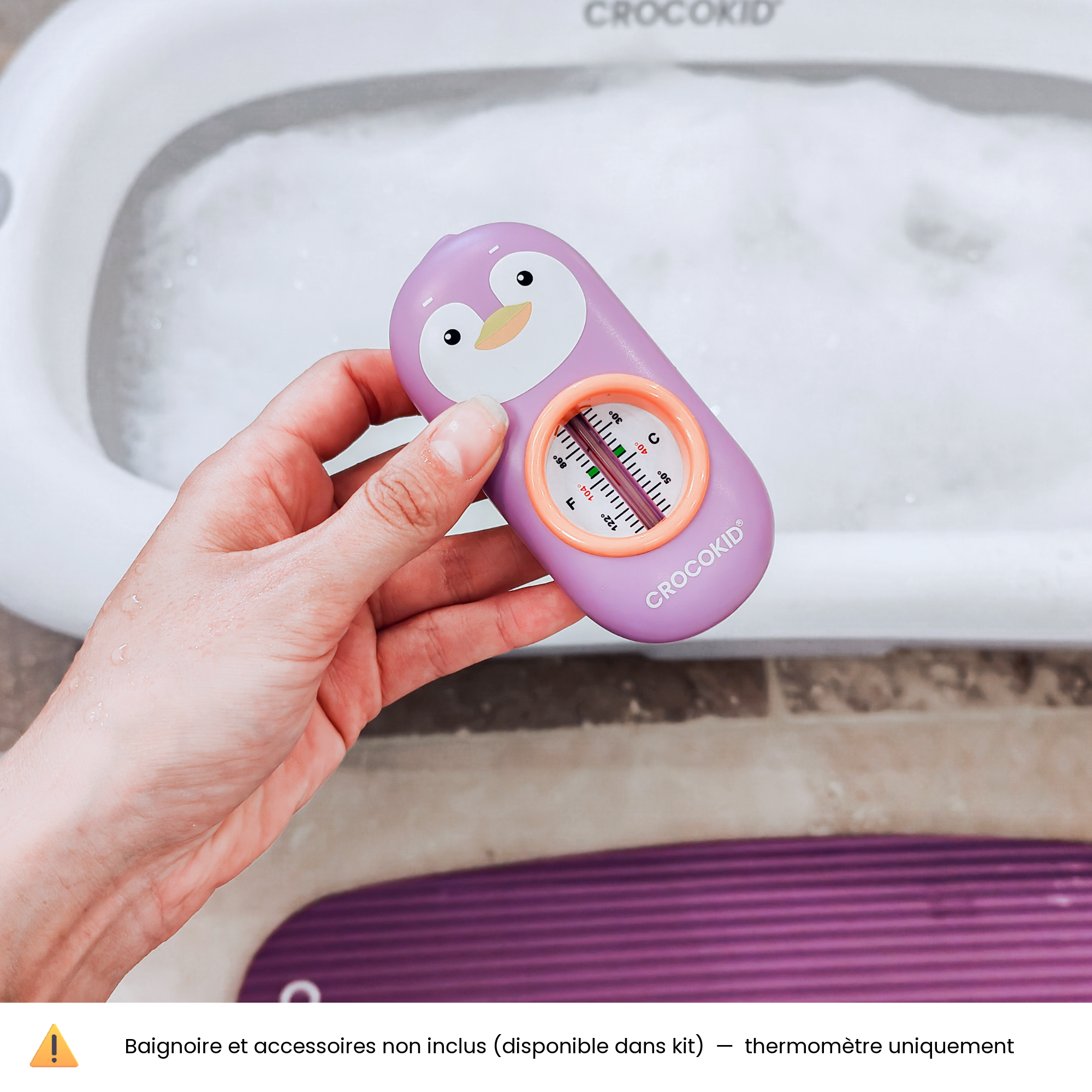 CROCOKID® Thermomètre de bain pingouin violet dans main devant baignoire - jouet ludique